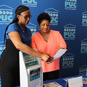 A PUC Consumer Education Specialist speaks with a community event attendee about utilities.